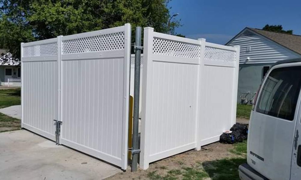 White vinyl privacy fence with decorative lattice top in a suburban yard, next to a white vehicle.