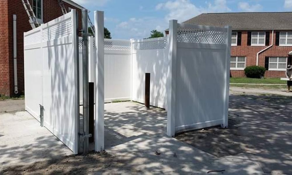 White vinyl privacy fence with lattice top installed near brick houses under a clear sky.
